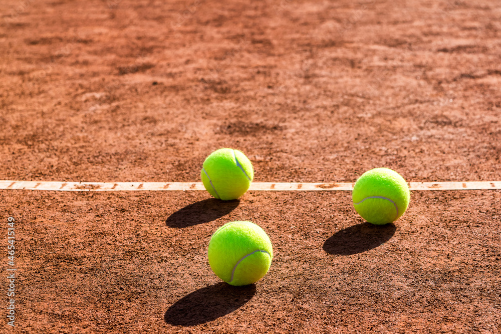 Close up of three tennis balls on a tennis clay court. Red clay court.