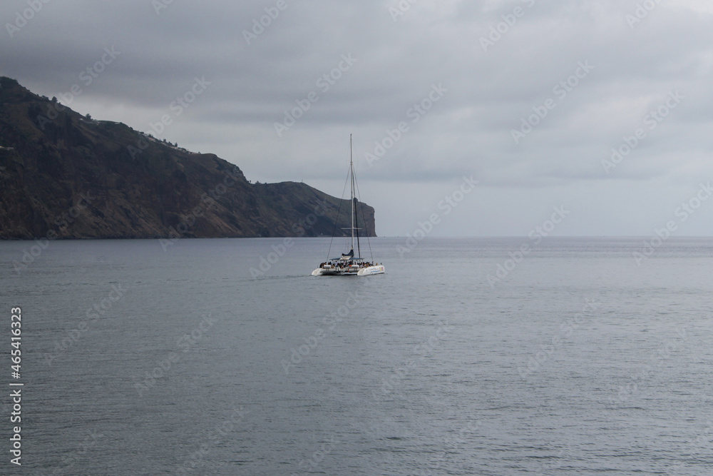 Boat catamaran with tourists, sailing  near the coast in Funchal, Portugal