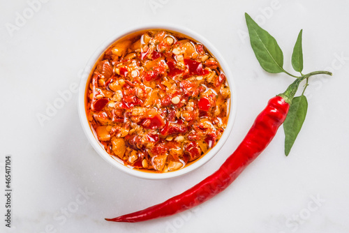 Chili red hot pepper sauce in oil  and fresh chili pepper on white marble background copy space. photo