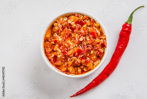 Chili hot pepper oil and fresh chili on white marble background copy space. photo