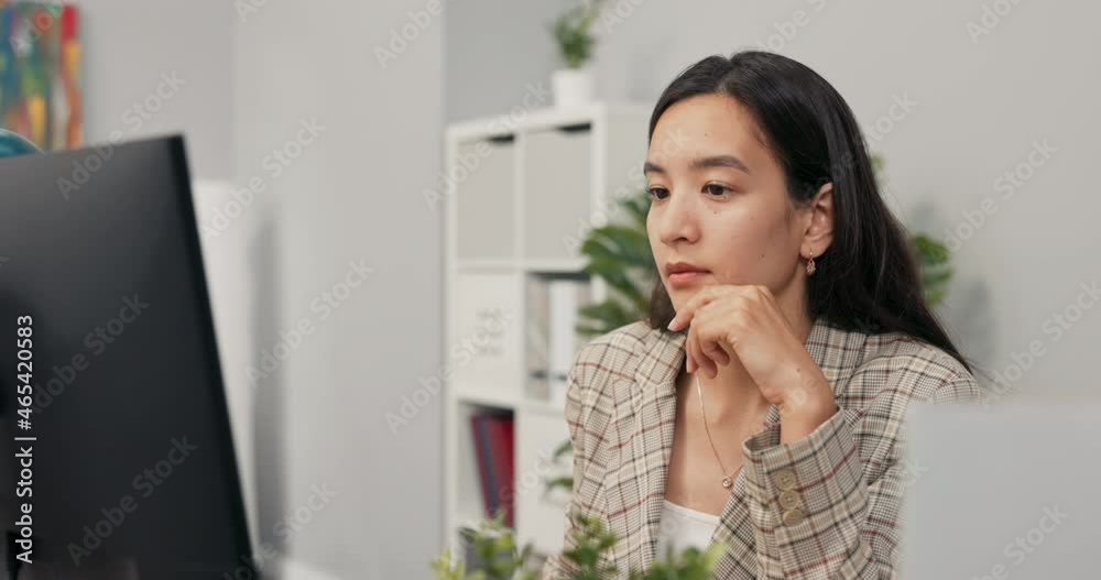 A focused pretty woman with long brown hair wearing a checkered jacket sits at desk in office in front of computer screen, reading news, articles, documents, analyzing propping hand under chin A focused pretty woman with long brown hair wearing a checkered jacket sits at desk in office in front of computer screen, reading news, articles, documents, analyzing propping hand under chin