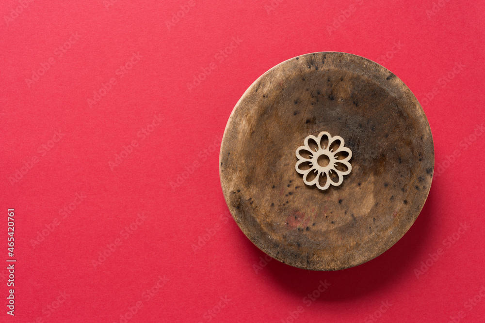grungy circular wooden object with laser cut flower shape on red paper grungy circular wooden object with laser cut flower shape on red paper