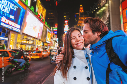 Selfie photo with phone by interracial couple tourists walking at Times Square in New York City on USA travel holiday vacation. Famous tourist destination.