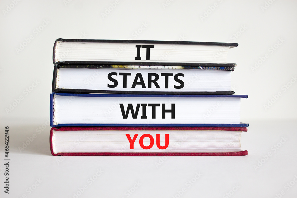 It starts with you symbol. Books with words 'it starts with you' on beautiful white background. Businessman hand. Business, motivational and it starts with you concept. Copy space.