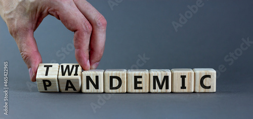 Pandemic or twindemic symbol. Doctor turns wooden cubes and changes the word 'pandemic' to 'twindemic'. Beautiful grey background, copy space. Medical and pandemic or twindemic concept.