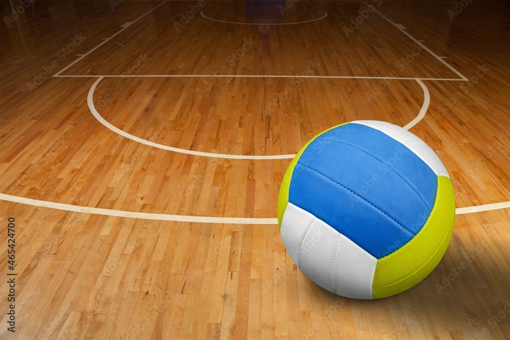 Volleyball ball on wooden parquet background.
