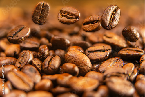 Arabica coffee beans, roasted aromatic fruits of the coffee tree. Grains in motion, macro photography.
