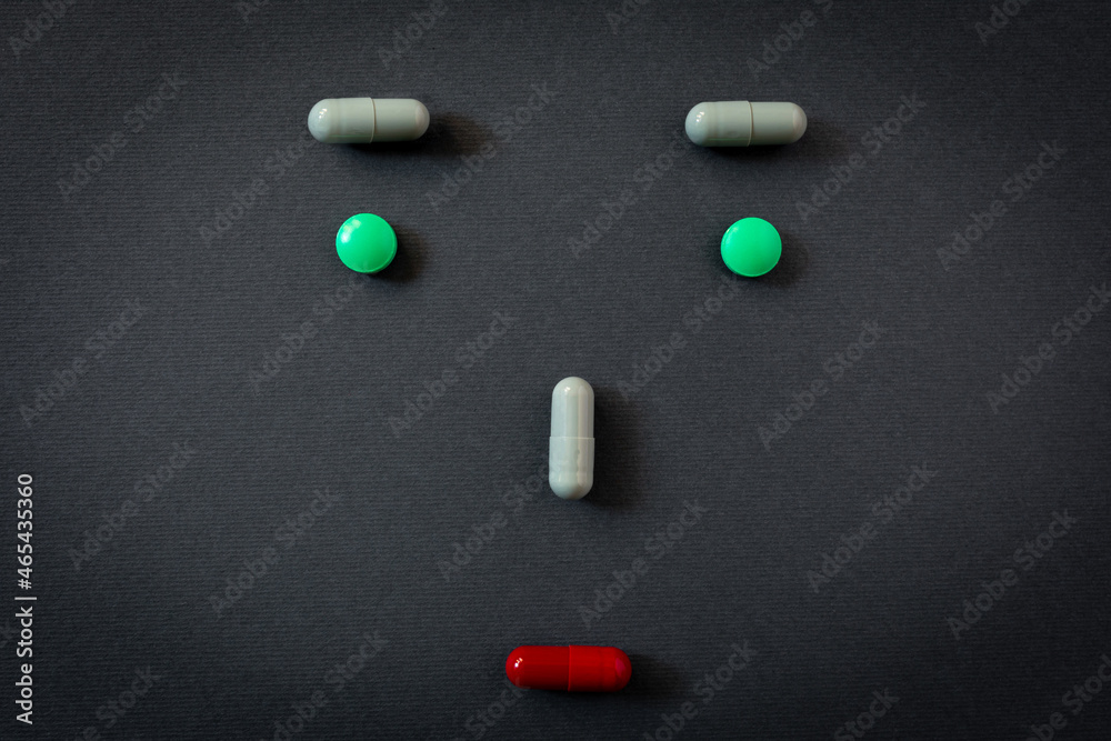 Creative emoticon, sad face of person realized with different tablets and pills of medicines on black background Creative emoticon, sad face of person realized with different tablets and pills of medicines on black background