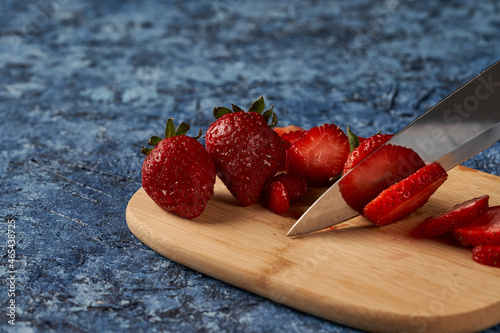 Fotografía knife cutting strawberry on wooden board