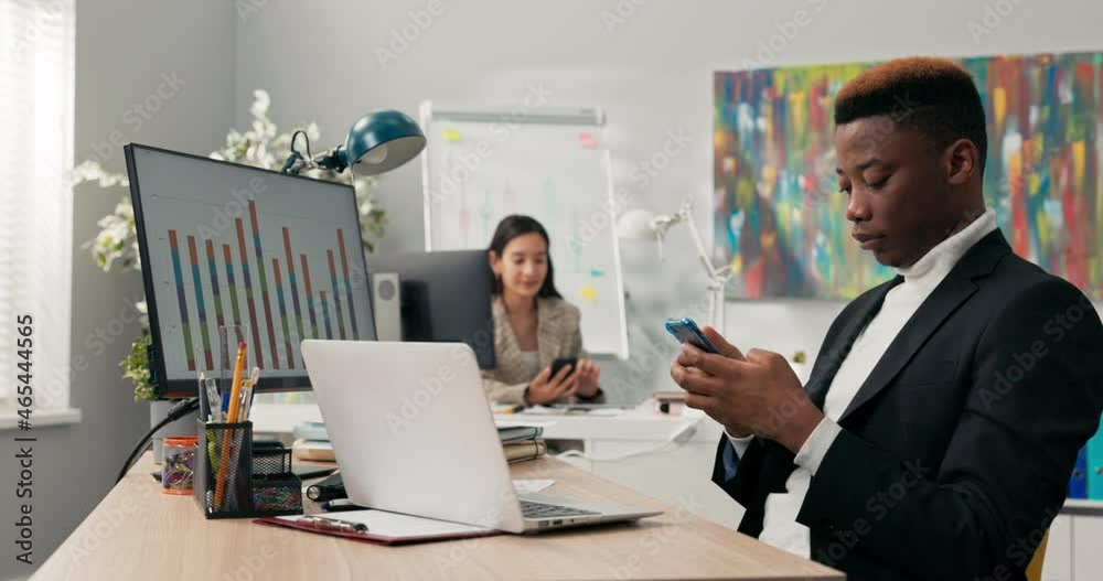Office workers sit at their desks in front of computer monitors, not attending to their duties, using phones, browsing social media, chatting with friends, a break from work, talking, laughing