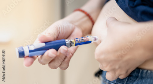 The diabetic patient hand using the insulin pen injection medical equipment to check and control the diabetics at home.