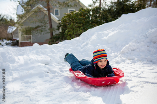 Happy young boy on a red sled in winter snow photo