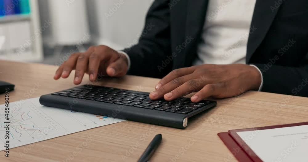 Close-up of a black keyboard from a computer standing on a wooden desk, a dark-skinned man with young hands is working at it, typing text on the keyboard, tapping fingers on the keys