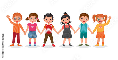 Group of happy cute children, boys and girls, standing together waving and holding hands showing happiness of friendship and unity.