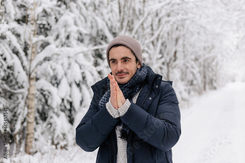 European Man Standing Smiling in WInter Forest Warming His Hands. Snowy Winter Day. Smiling Man Cold