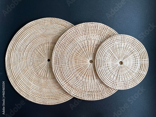 Round shape woven rattan placemat on black background, handmade kitchenware, weave craft product 