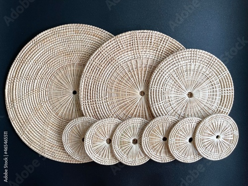 Round shape woven rattan placemat on black background, handmade kitchenware, weave craft product 