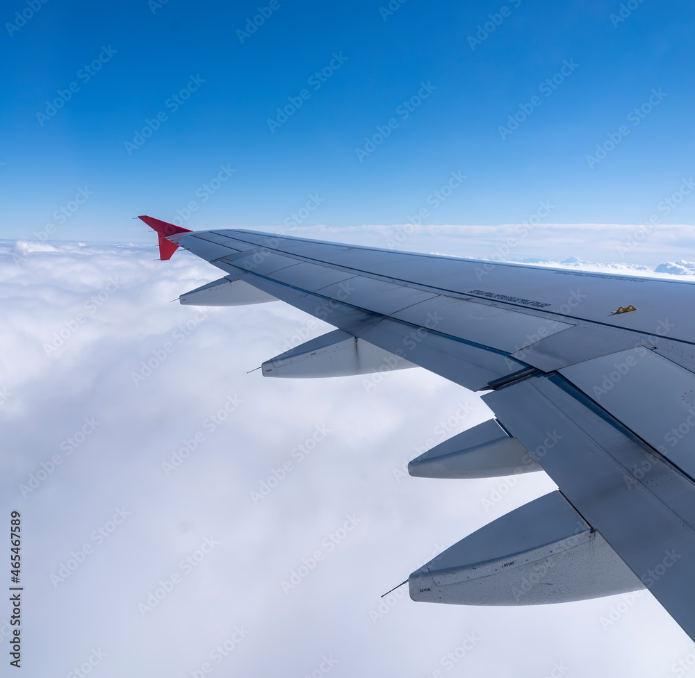 View of an airplane wing and land and sky as background. View of an airplane wing and land and sky as background.