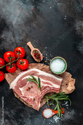Fresh raw pork meat with ingredients ready for cooking on black table. vertical image. top view. place for text