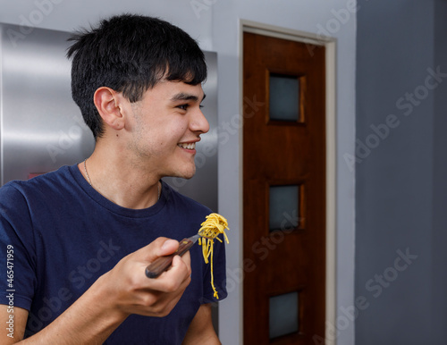 latin man eating italian pasta, smiles happily.