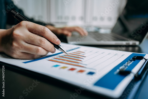 Close up of Businesswomen or Accountant working on laptop computer with analytic business report graph and finance chart at the workplace, financial and investment concept.