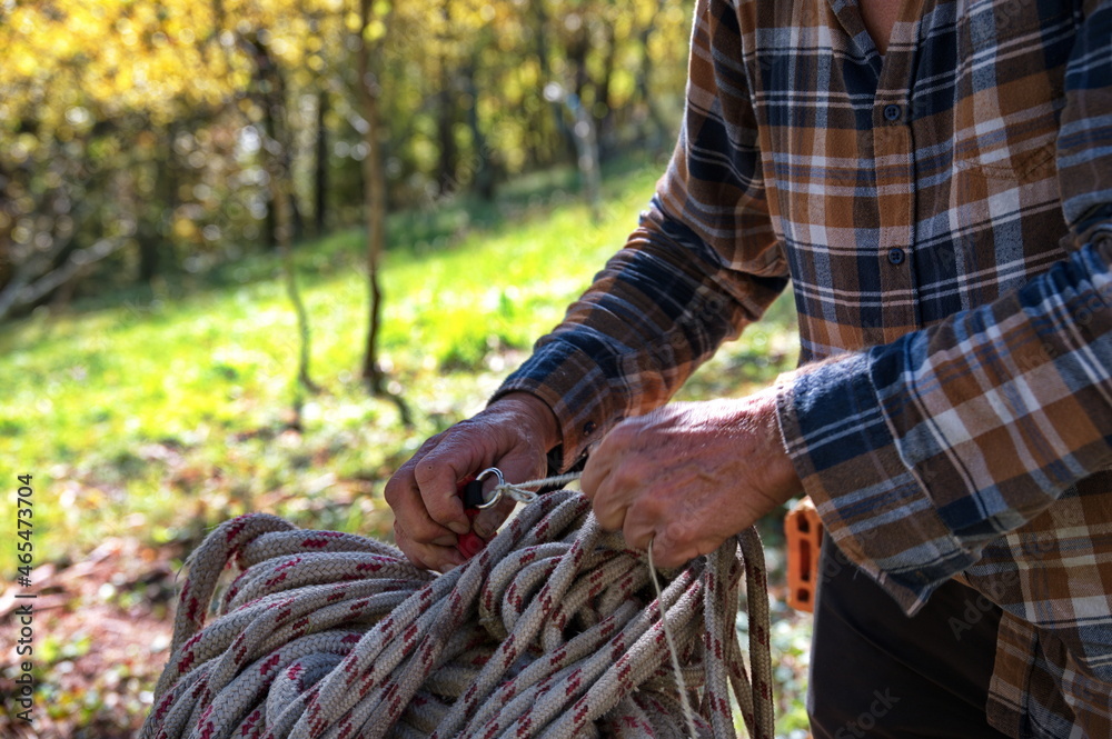 Midsection of man preparing rope for work in forest