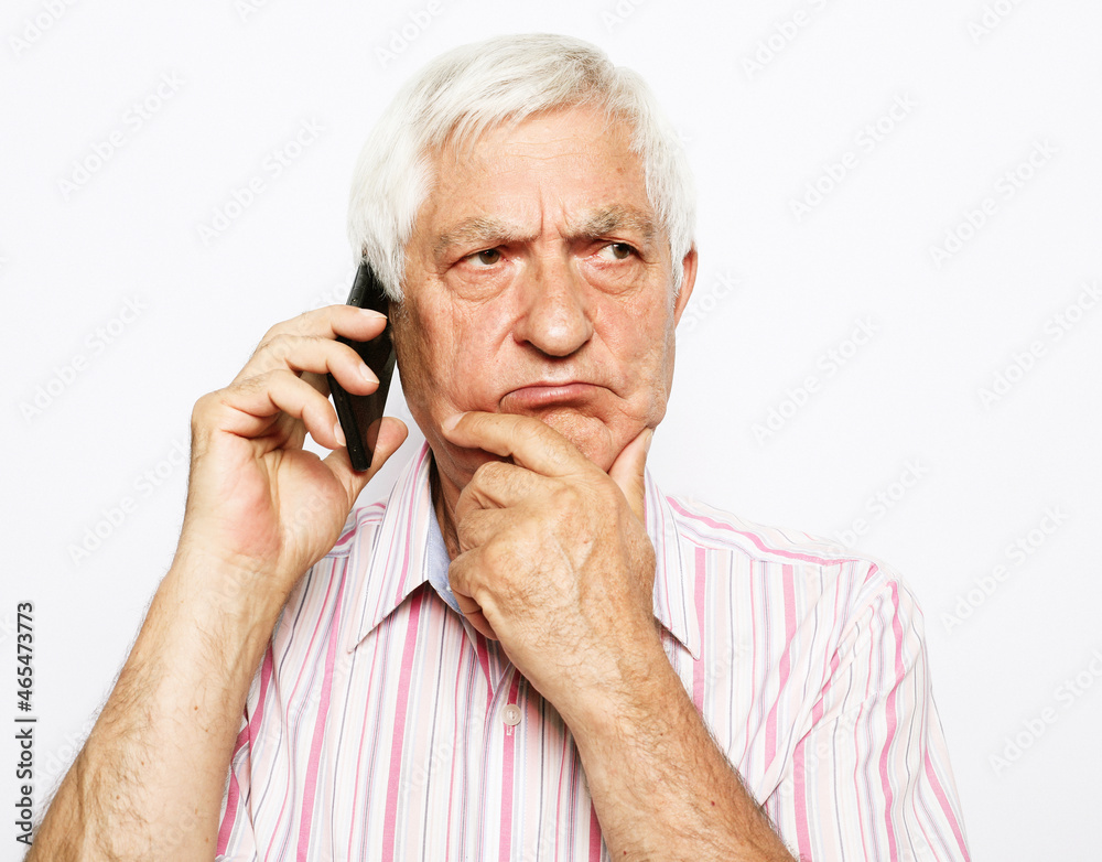 Senior man talking on mobile phone, doubts, difficult choice, touches chin with hand Senior man talking on mobile phone, doubts, difficult choice, touches chin with hand