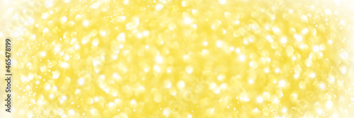 Defocused Christmas yellow background. Holiday abstract glitter defocused background with blinking bokeh.Holiday glowing backdrop.Banner.
