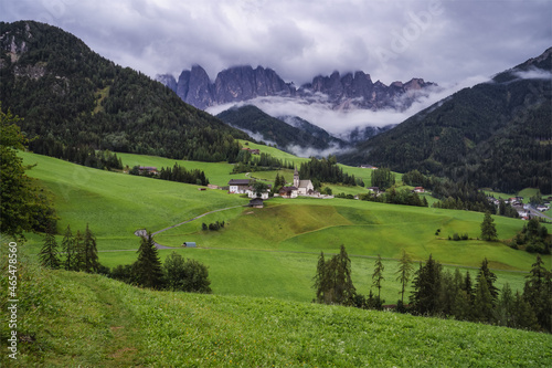 St Magdalena church in Val di Funes valley, Dolomites, Italy. Furchetta and Sass Rigais mountain peaks in background photo