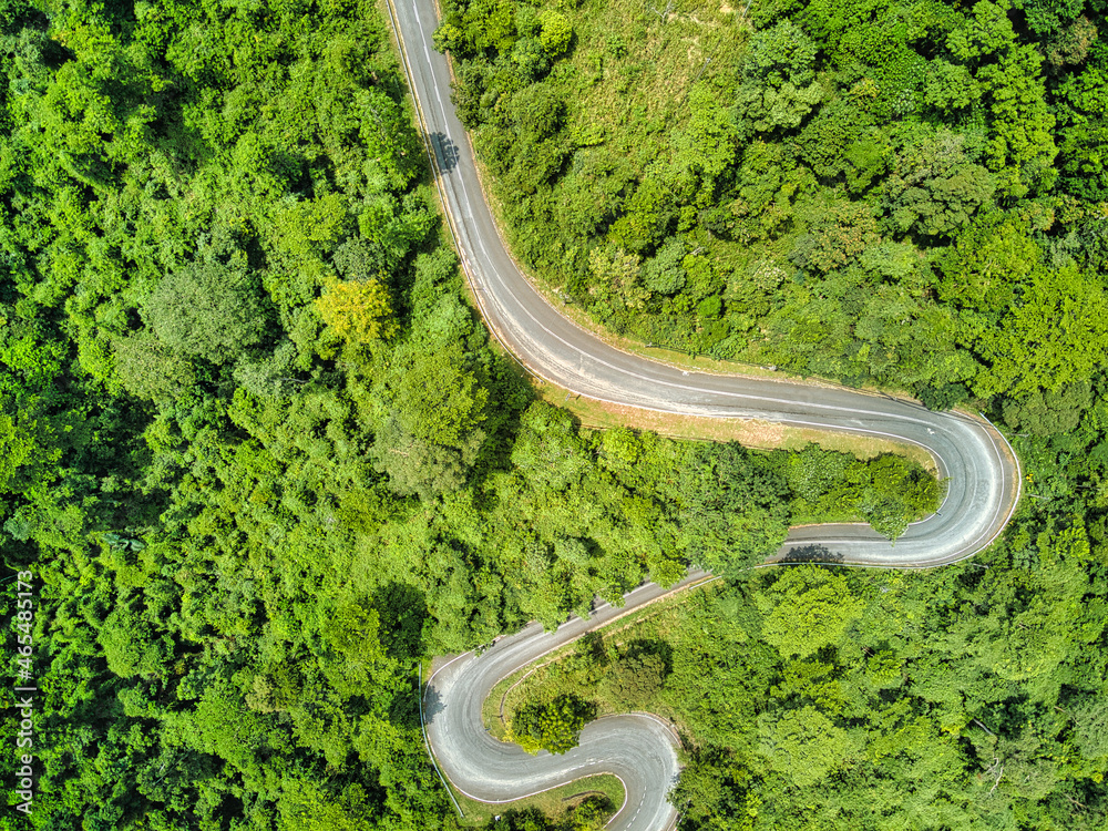 Winding road trough the mountain forest. Top aerial view
