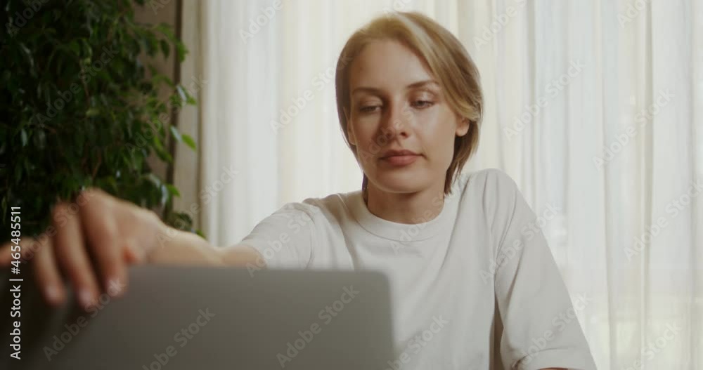 Young woman sits down at the breakfast table, opens a laptop and drinks coffee Young woman sits down at the breakfast table, opens a laptop and drinks coffee