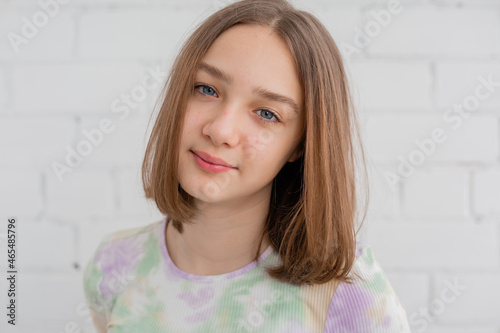 portrait of a slender teenage girl in a light turtleneck in natural light against a white brick wall. natural beauty, no makeup. problematic skin. space for text. High quality photo