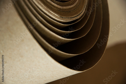 kraft paper roll. curled beige material close up. cardboard production concept