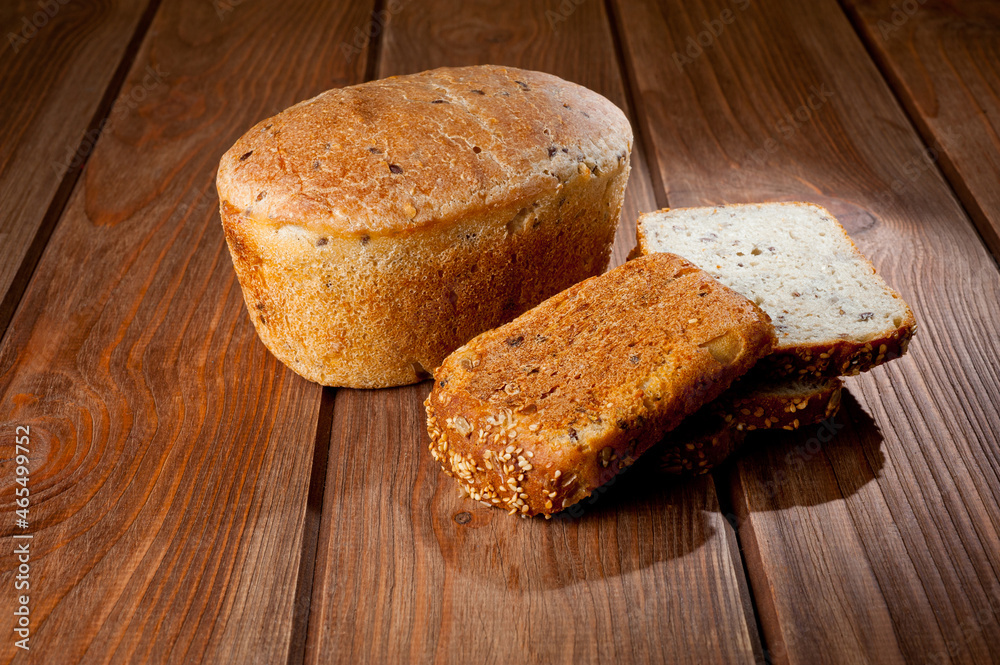 A loaf of delicious white bread made from natural products, on hops with flax saturation, without baker's yeast, on a wooden table surface. A loaf of delicious white bread made from natural products, on hops with flax saturation, without baker's yeast, on a wooden table surface.