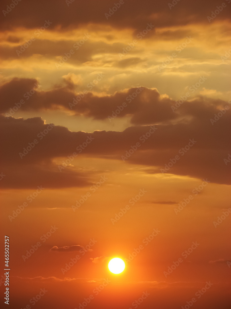 Vibrant sunset - sun surrounded by fluffy clouds