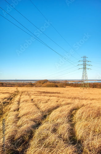 Rural landscape with high voltage transmission tower on a field.