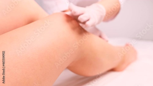 Beautician wearing medical gloves making massage procedures to a woman legs after the depilation with wax or shugaring photo