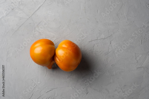 Fresh raw ugly tomato on gray background.