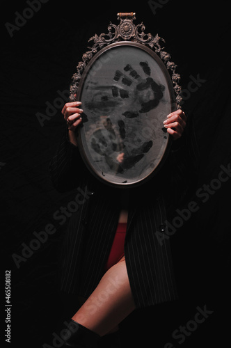 Girl holding a mirror with her hands. Costume on Halloween.