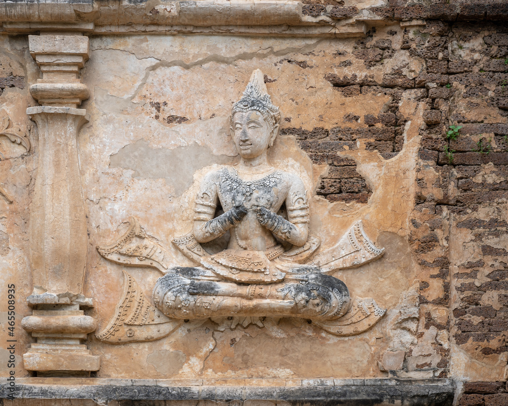 Beautiful ancient stucco life size carving of sitting deity on wall of Wat Chet Yot or Wat Jed Yod buddhist temple, historic landmark of Chiang Mai, Thailand