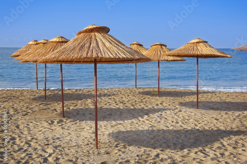 Thatched umbrellas on the beach by the sea.