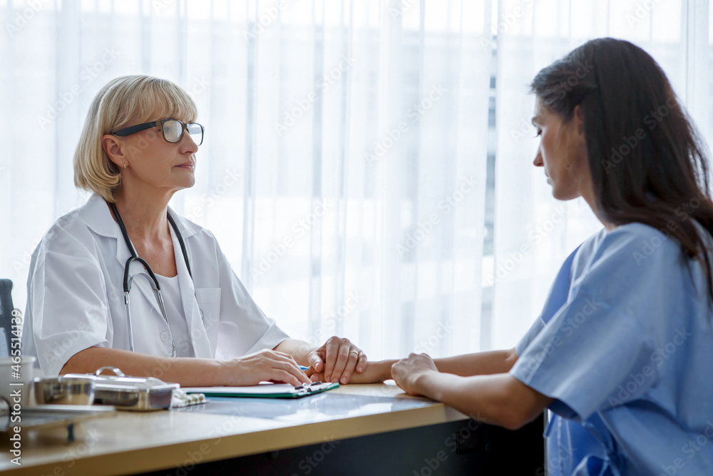 Obraz premium Senior female doctor discussing with young woman patient in clinic at hospital