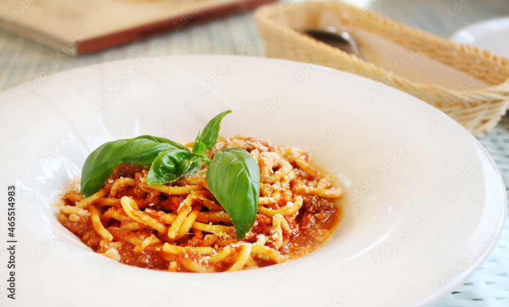 pasta Bolognese with leaves of fresh basil on table