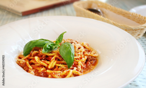 pasta Bolognese with leaves of fresh basil on table