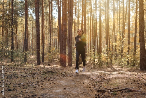 Young athletic woman jogging in forest in sunny morning. Healthy lifestyle concept. © natapetrovich