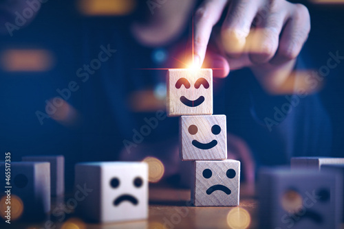 Businessman hand holding touching smile face or happy face which print screen on wooden cube block, Business service rating , Satisfaction concept.Selection and Choosing emotion or mood concept.