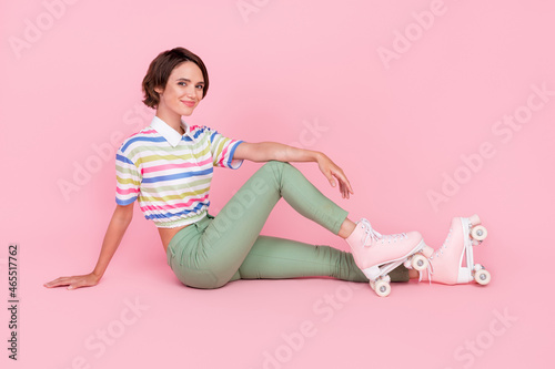 Full length photo of young beautiful girl happy positive smile sit floor skater rest isolated over pastel color background