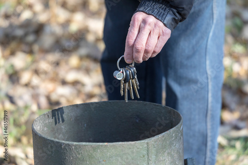 An old man throws a bunch of keys in the trash