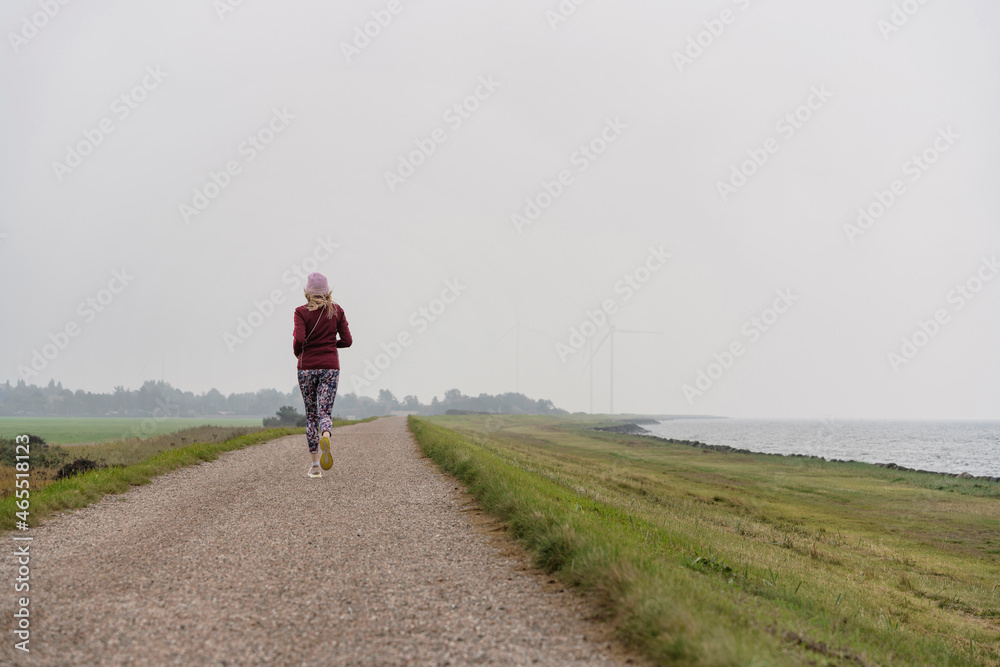 Obraz premium Frau joggt auf Damm im Herbst
