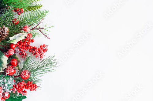 Christmas tree twig with red berries and cone on a white background, copy space